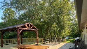 An outdoor patio with a wooden pergola, picnic table, and wicker chairs. - Parkview at Cataract Falls Lodge.   (Spencer)
