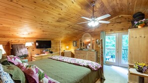 Ein gemütliches Schlafzimmer im Chalet-Stil mit einem großen Bett, einem Schminktisch, einer Kommode und einem Deckenventilator.