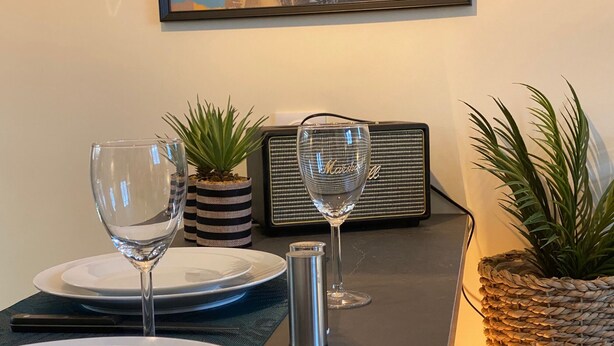 Een eettafel gedekt met borden, glazen en een kleine potplant.