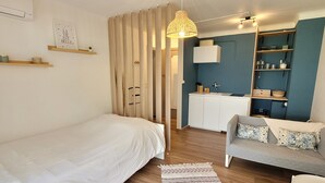 Ein kompakter Raum mit Bett, einer Schlafcouch, einer Küchenzeile und einem Essbereich.