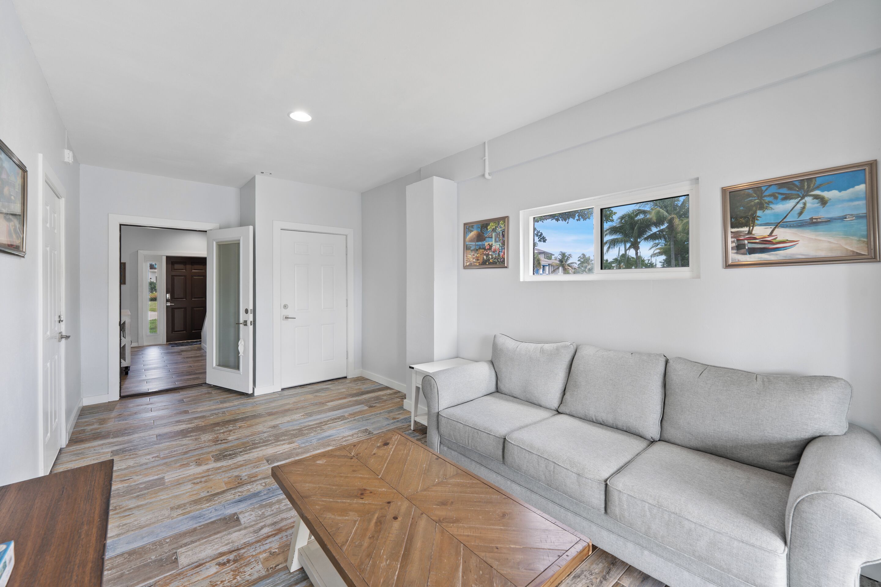 Un salon moderne avec un canapé gris, une table basse en bois et un couloir menant à une autre pièce.