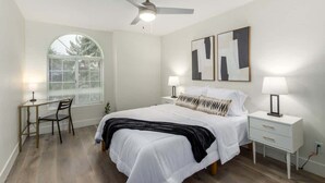 Een slaapkamer met een bed, twee nachtkastjes, een bureau en een stoel.