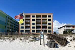 A multi-story hotel with balconies, a sandy beach in front, and a wooden boardwalk. - Harbour Place 511 3 Bedroom Condo by RedAwning (Orange Beach)