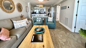 A living room with a sofa, two armchairs, a coffee table, and a ceiling fan. - Harbour Place 511 3 Bedroom Condo by RedAwning (Orange Beach)