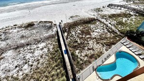 A beach view with a wooden boardwalk leading to a pool area. - Harbour Place 511 3 Bedroom Condo by RedAwning (Orange Beach)
