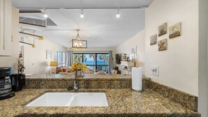 A kitchen with granite countertops, a white sink, and a coffee maker.
