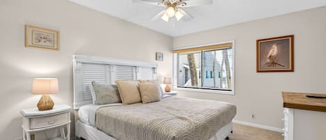 Un dormitorio con cama, mesitas de noche, ventilador de techo y ventana con persianas.