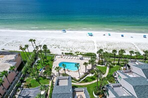 Un resort con piscina, acceso a la playa y palmeras.