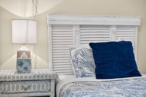 Un dormitorio con cama, mesita de noche, lámpara y una caja decorativa.