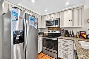 Una cocina moderna con electrodomésticos de acero inoxidable, armarios blancos y encimeras de granito.