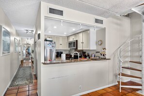 Una cocina moderna con armarios blancos, electrodomésticos de acero inoxidable y una isla central.