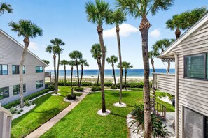 Un barrio residencial con césped, palmeras y vista a la playa.