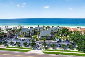Ein Hotel an der Küste mit Parkplatz, Blick auf den Strand und Palmen.