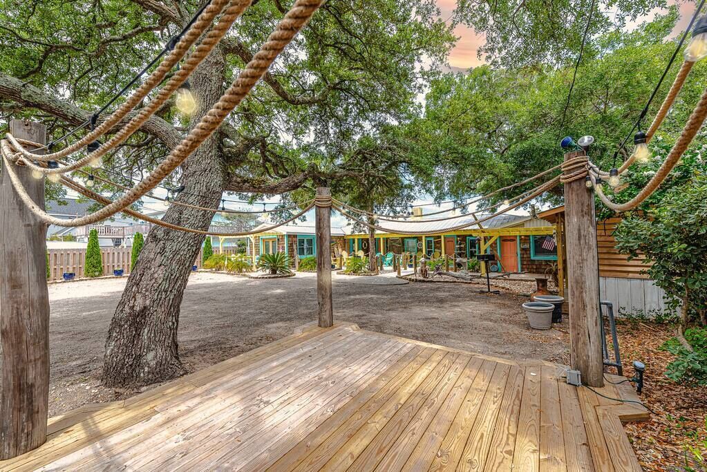 A wooden deck with rope swings, a large tree, and a building with a yellow roof in the background.