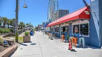 A restaurant with a red awning and outdoor seating.