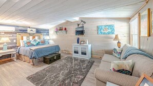 Un dormitorio acogedor con una cama, un sofá, un armario pequeño y una alfombra.