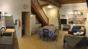 Un espacio habitable compacto con cocina, comedor y una escalera que conduce a un nivel superior.