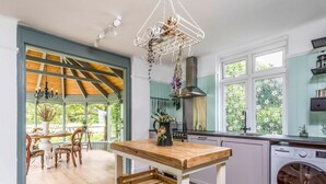 Een keuken met een houten tafel, een wasmachine en een eethoek met stoelen en een tafel.