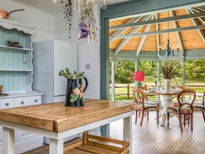 Comedor con mesa de madera, sillas y vistas al exterior a través de amplios ventanales.