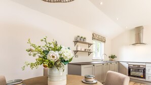 Una cocina moderna con una mesa redonda, suelo de madera clara y un jarrón con flores.