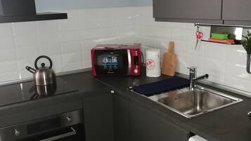 Une cuisine compacte équipée d’un four à micro-ondes, d’une bouilloire, d’un four et d’un lave-linge.