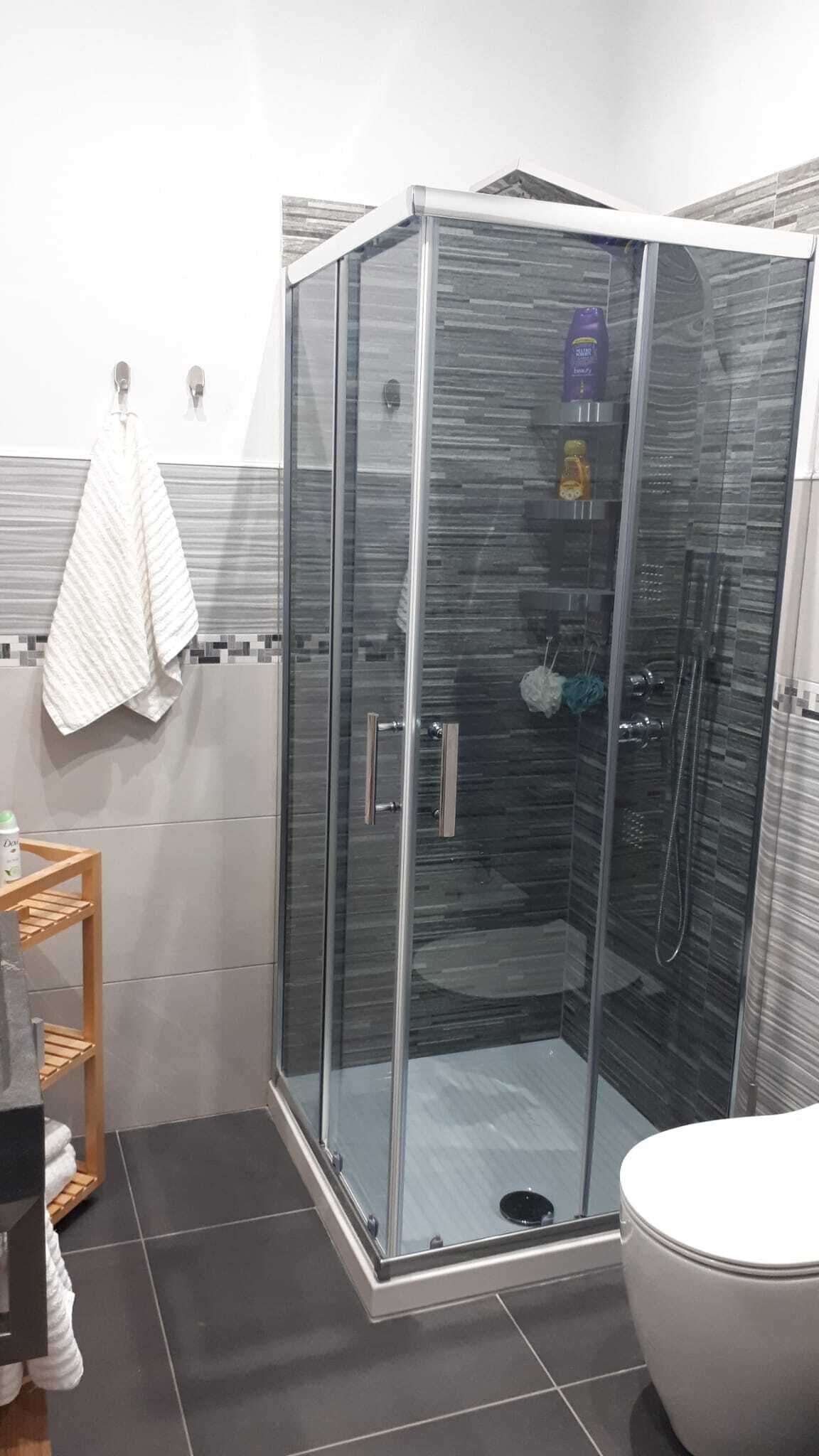 Un baño moderno con ducha de mampara de vidrio, inodoro y barra para toallas.