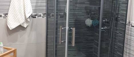 Un baño moderno con ducha de mampara de vidrio, inodoro y barra para toallas.