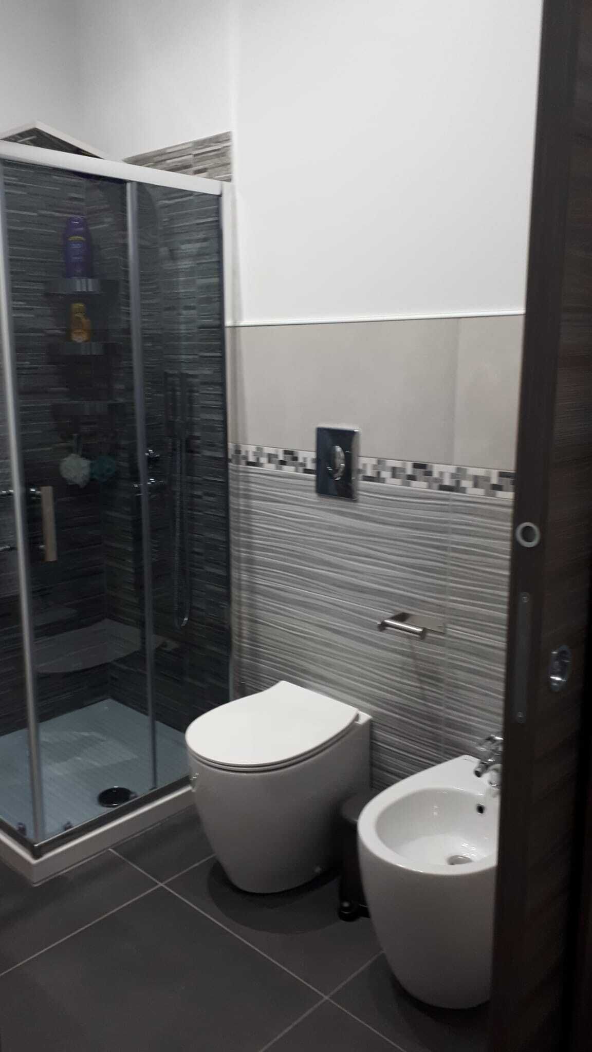 Ein Badezimmer mit einer Duschkabine, zwei Toiletten und einem Bidet.
