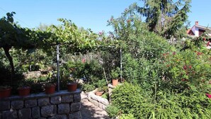 A garden with a stone wall, potted plants, and a pergola.