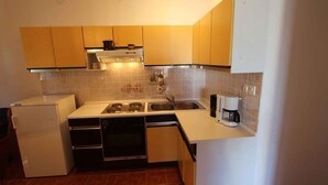 A compact kitchen with a refrigerator, stove, oven, and coffee maker.