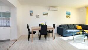 Ein modernes Wohnzimmer mit Essbereich, einer Couch und einem Glastisch.