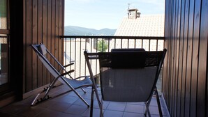 Een balkon met uitzicht op bergen, een stoel en een tafel.
