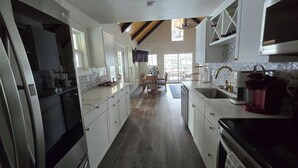A modern kitchen with white cabinetry, a black stove, and a dining area with a table and chairs. - MT dreams create memories that last a lifetime ❄️ Winter Land ☀️ Summer serenity (Marion)
