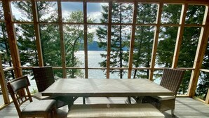 A wooden deck with a picnic table and chairs, overlooking a lake with trees. - MT dreams create memories that last a lifetime ❄️ Winter Land ☀️ Summer serenity (Marion)
