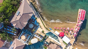 An aerial view of a resort with a beach area, including sun loungers and umbrellas, and a pool area with a glass facade. - Carpe Diem Boutique Hotel - Adults Only (Manavgat)