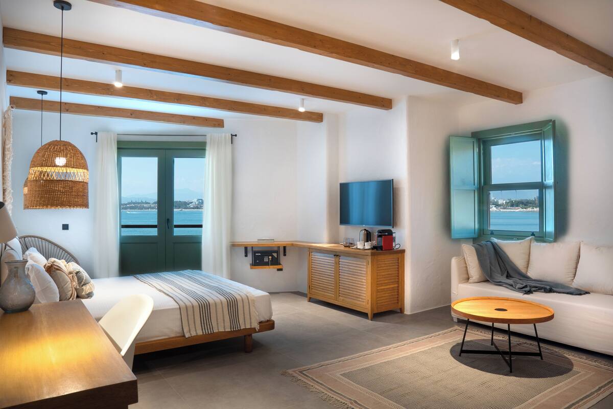 A modern bedroom with a bed, a sofa, a coffee table, and a TV.