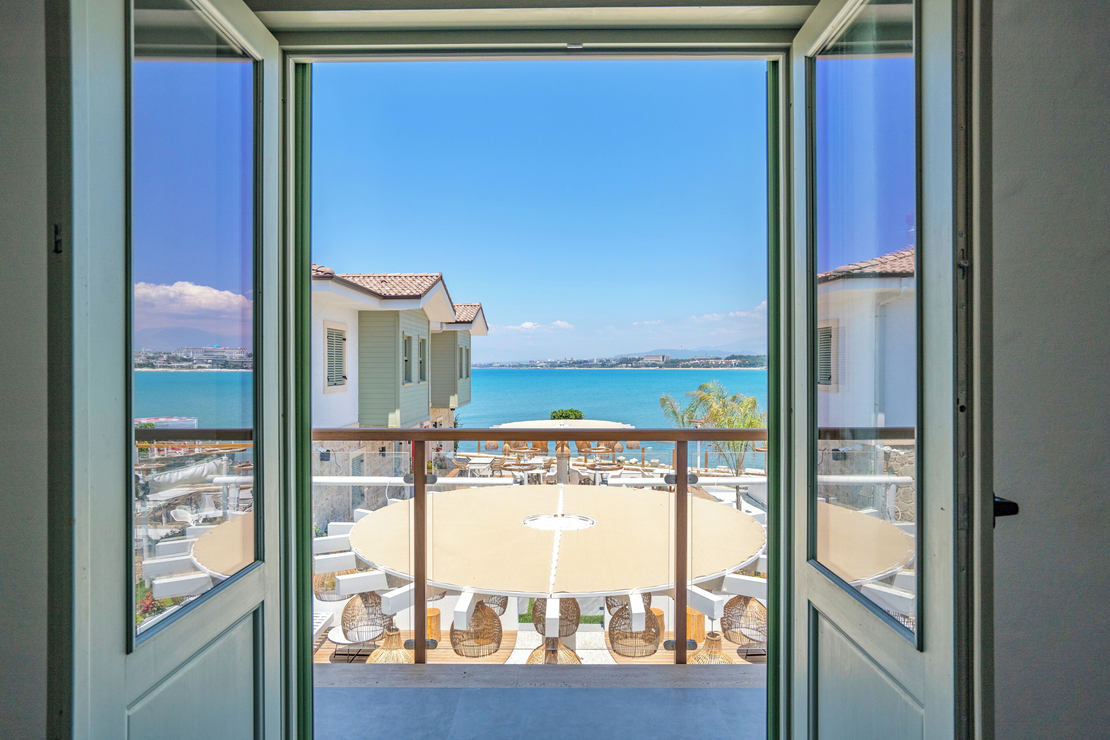 A balcony with a view of the sea, a round table, and outdoor seating.