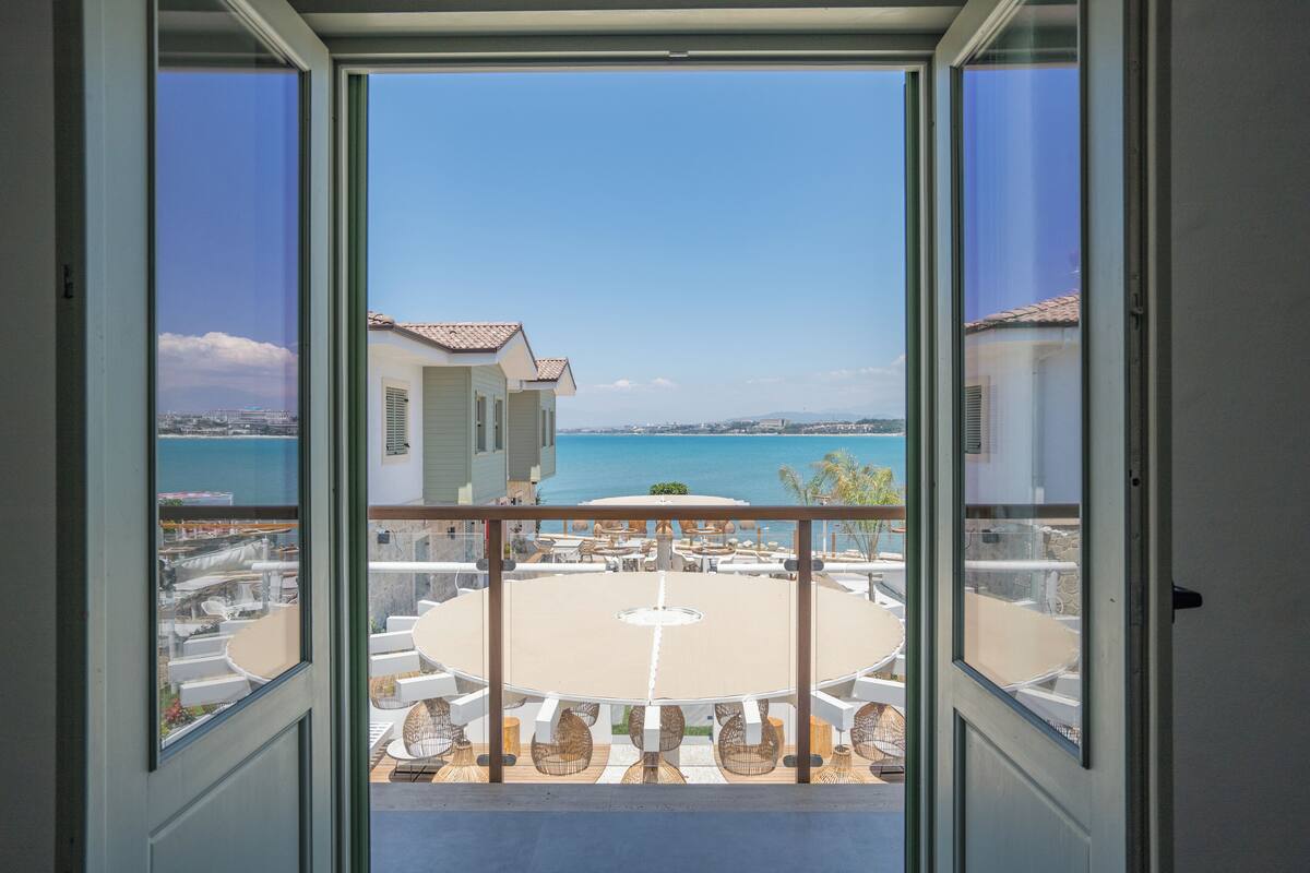 A balcony with a view of a pool and a building across the water.