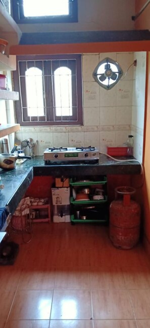 Kitchen features a gas stove, refrigerator, and gas cylinder, with a window above the sink.