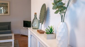 Ett vardagsrum med en vit öppen spis, en tv på ett tv-bord och en inramad tavla på väggen.