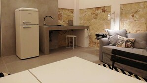 A compact living space with a kitchenette, a sofa, and a dining table. - Casa Lunya (siracusa)