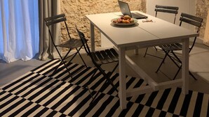 A modern dining area with a white table, black and white striped rug, and a laptop on the table. - Casa Lunya (siracusa)