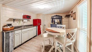Eine kleine Küche mit weißen Schränken, einem roten Kühlschrank und einem Holzespeisetisch mit weißen Stühlen.