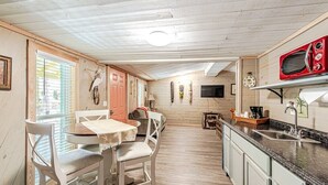 Eine kompakte Küche mit Essbereich, Holzwänden, einer roten Mikrowelle und einem kleinen Tisch mit Stühlen.