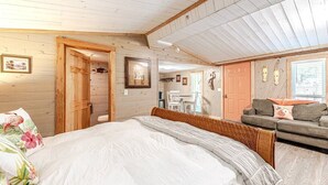 Ein Schlafzimmer mit einem großen Bett, einer Holztür, einem kleinen Tisch und einem Sofa.