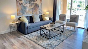 A modern living room with a grey sofa, a coffee table, and a large abstract painting on the wall. - LUXURY THE YATCH 301- FREE PARKING AND WIFI (Aventura)
