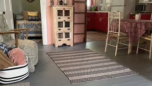 Ein gemütliches Wohnzimmer mit einem gemusterten Teppich, einem Holzschrank und einem Essbereich mit Tisch und Stühlen.