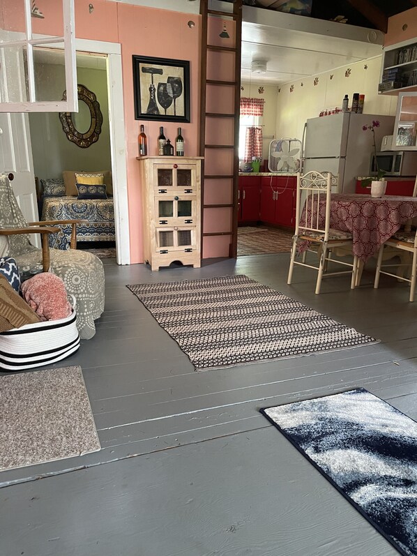 Una sala de estar acogedora con un tapete estampado, un aparador de madera y un comedor con mesa y sillas.