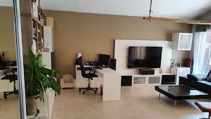 A modern living room with a desk, chair, TV, and a sofa.