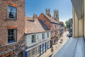 Une vue d’une rue bordée de bâtiments traditionnels en briques, d’une église dotée d’un clocher imposant et d’une enseigne indiquant l’emplacement d’une salle de lecture de la Christian Science.